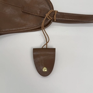Detail of brown leather bag showing precise stitching and golden metallic magnetic snap