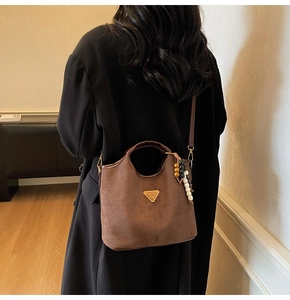 Gros plan d'un sac seau en daim marron mat avec perles décoratives en bois et bandoulière