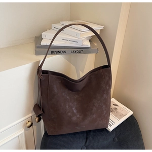 Detail of vintage dark brown tote bag with matte texture on a soft velvet stool