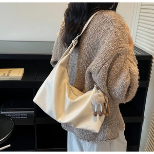 Détail du grand sac hobo crème avec bandoulière et pendentif en peluche marron