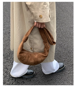 Détail d'un sac croissant en daim marron avec matelassage plissé et large bandoulière
