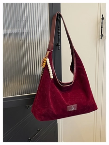 Détail du sac à bandoulière en daim bordeaux vintage avec breloque en bois