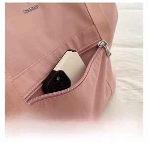 Gros plan détaillé de la poche avant zippée d'un sac de voyage rose en tissu Oxford