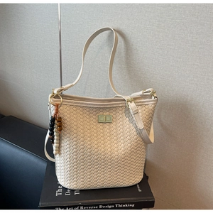 Detail einer geflochtenen Beuteltasche mit Goldverschluss und bunten Perlenanhängern