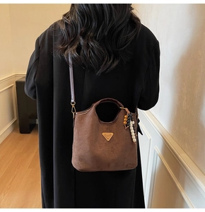 Sac seau marron mat avec breloque en perles et logo sur une tenue avec manteau noir