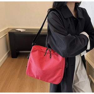 Detail view of red plaid tote bag with adjustable black strap and dual zipper closure