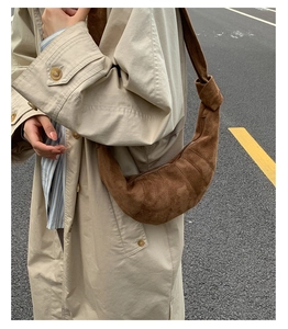 Détail d'un sac croissant en daim marron foncé avec bandoulière nouée et texture matelassée