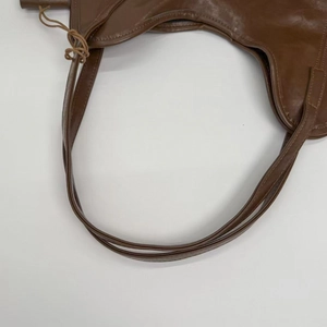 Close-up of double thin straps and fine stitching on a brown leather shoulder bag
