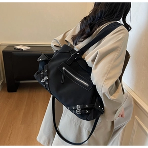 Detail of punk style black functional tote bag with silver buckles and zipper pockets