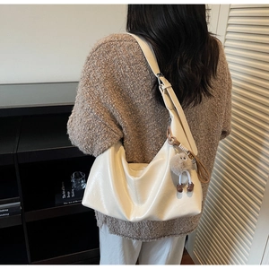 Détail du sac hobo crème en similicuir souple avec un pendentif en peluche gris foncé