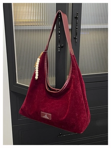 Détail du sac hobo en velours rouge foncé avec lanières en cuir et accessoire en perles