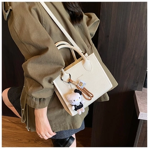 White pebbled leather tote bag with long shoulder strap and cute plush charm detail