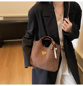 Gros plan du sac seau en daim marron mat avec breloque en perles sur un mannequin