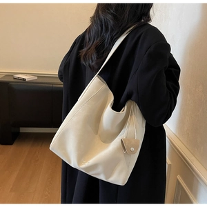 Detail of off-white hobo bag with a small coin purse charm on black coat