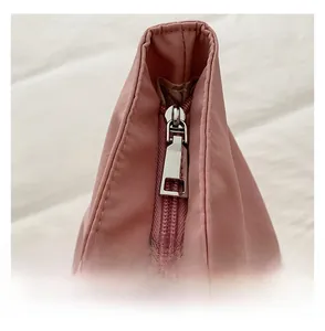 Détail de la pochette en nylon rose montrant la fermeture éclair en métal argenté