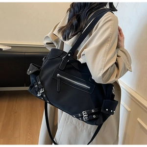 Détail d'un sac cabas punk noir avec œillets métalliques et sangles industrielles