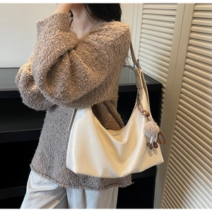 Détail d'un grand sac hobo beige avec un charme en peluche et bandoulière réglable