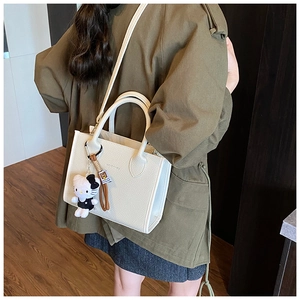 Close-up of cream-white bucket bag with HOGOMU logo and cute plush kitty charm