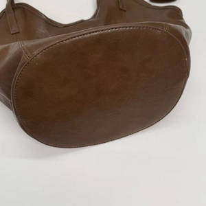 Detailed macro view showing the oval base and reinforced stitching of the brown tote bag