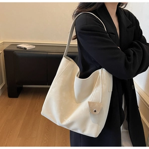 Detailed macro view of beige large capacity faux leather tote bag with elegant strap charm