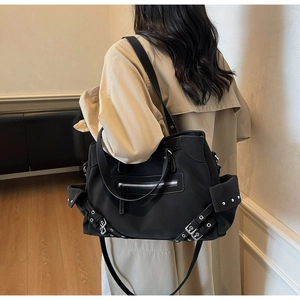 Detail of vintage black matte tote bag with silver zippers and studs on a trench coat model
