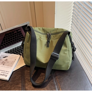 Detail of green plaid nylon crossbody bag with dual zippers and adjustable shoulder strap