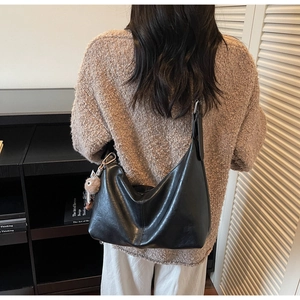 Détail du sac à main noir en similicuir avec un joli pendentif d'ours en peluche marron