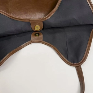 Detail shot of the magnetic snap closure and black fabric lining of the brown leather bag