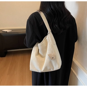 Close-up of ivory leather tote bag with large capacity and decorative triangle pendant