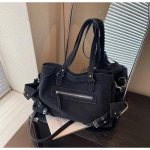 Detail of black matte tote bag featuring silver rivets, zipper pockets and industrial buckles