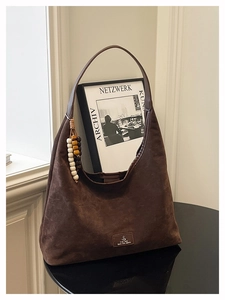 Détail du sac cabas en daim marron foncé avec surface texturée et breloque en perles de bois