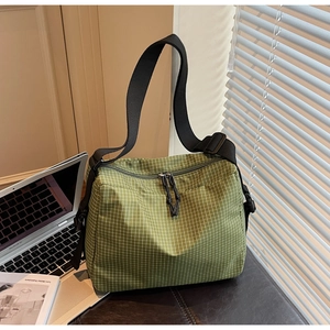 Detail of green checkerboard canvas tote with adjustable strap on desk setting
