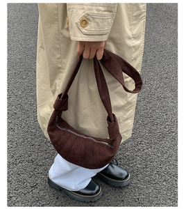 Détail d'un sac demi-lune en daim marron foncé avec bandoulière nouée et coutures