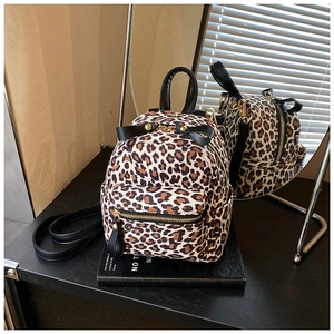 Detail view of leopard print mini backpack with black bow and golden zipper accents