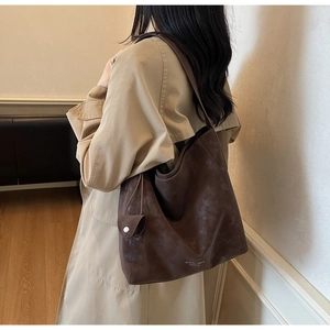 Detail of dark brown tote bag in vintage matte leather with side pouch and shoulder strap