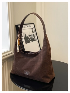 Détails de la texture du sac porté épaule en daim marron foncé avec des perles en bois