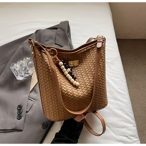 Nahaufnahme der dunkelbraunen Web-Eimertasche mit goldener Schnalle und Perlenanhänger