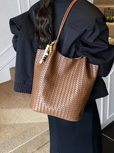 Brown woven leather tote bag with decorative beads shown on model in modern setting