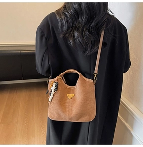Détail d'un sac seau en daim marron mat avec logo doré et breloque en perles colorées