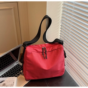 Detail of red checkered canvas tote bag with adjustable wide black strap and dual zippers