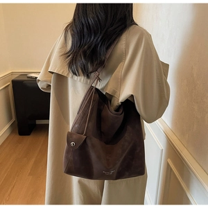 Detail of vintage brown tote bag with suede texture and logo worn over the shoulder