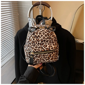 Detail view of leopard print mini backpack featuring black bow and gold hardware accents