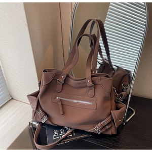 Detailed close-up of brown matte tote bag with vintage metal buckles and zipper