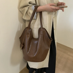 Detail of dark brown leather tote bag with curved rim and mini pouch accessory