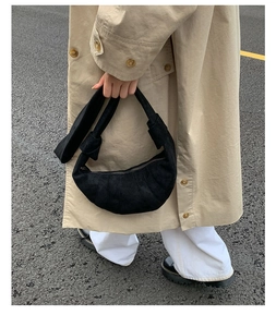 Détail d'un sac croissant noir en daim avec plis élégants et bandoulière à nœud unique