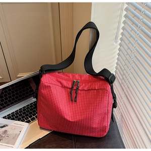 Detail of red checkered canvas crossbody bag with adjustable strap and double zipper