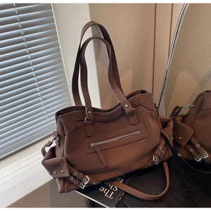 Detail of dark brown leather tote bag with metallic studs and vintage buckle accents