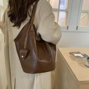 Dark brown large capacity tote bag shown on a model in a cozy indoor setting