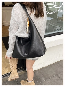 Détail du sac hobo noir en similicuir avec pompon en perles de bois en ville