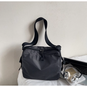 Detail of checkered canvas tote bag with adjustable shoulder strap and dual zippers